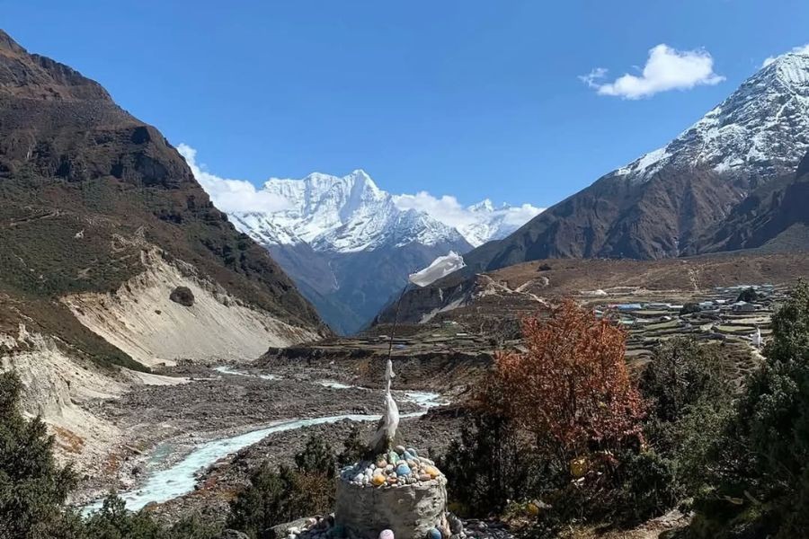 Autumn trail scenery with Buddhist stupa, river valley, and distant Himalayan mountains